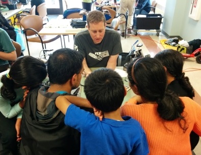 man showing people around a table how to fix something