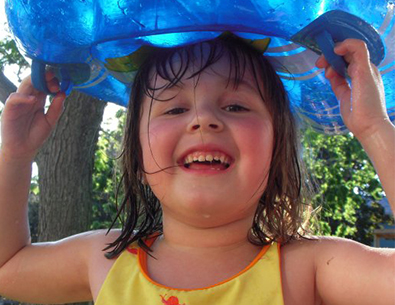 little girl outside in summer with a floatie on her head