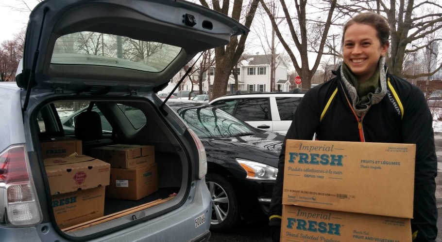 person putting a box of food in the trunk of a car