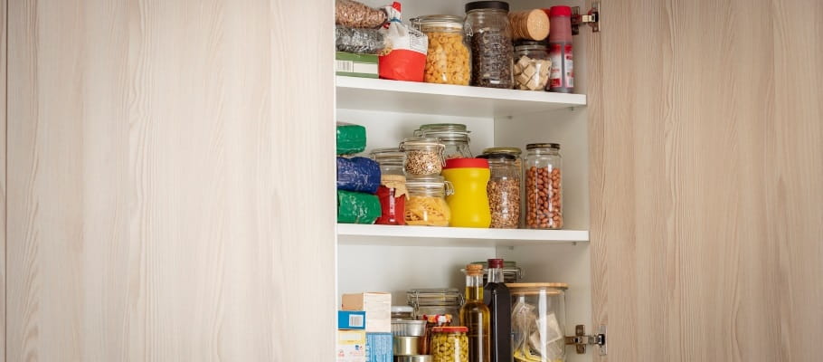 Close-up of a kitchen cabinet with the door open showing organized spices and dry goods