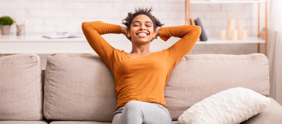 Person reclining on couch with hands behind head, generally happy and relaxed
