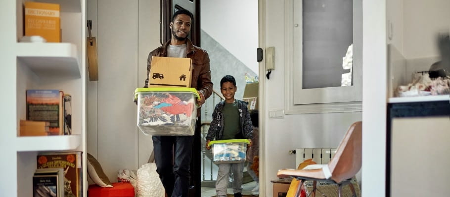 Adult and child carrying totes of organized items into a room