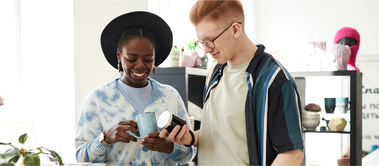 Two people browsing mugs at a thrift store