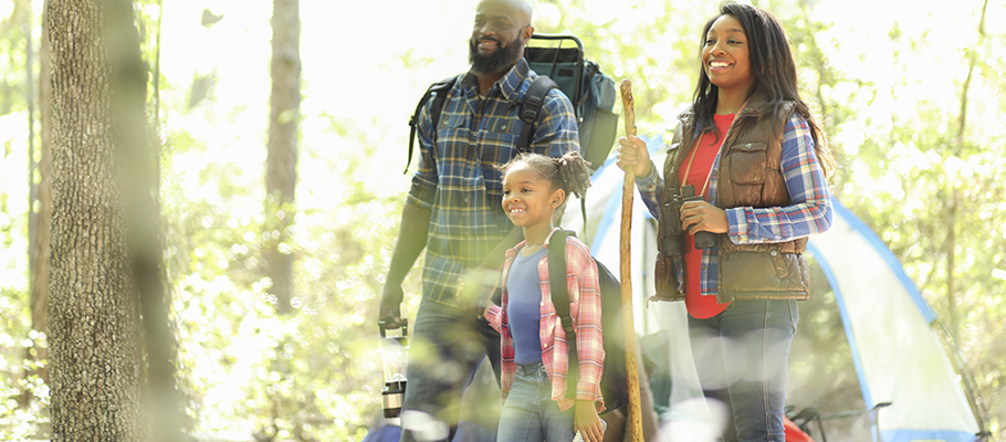 Two parents and child with backpacks on hiking in woods